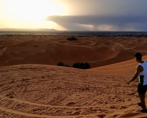 Travellers on a camel trek across Moroccan desert dunes