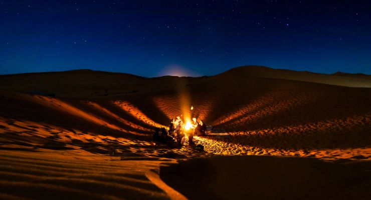 Camel trekking caravan crossing small dunes near M'Hamid, Morocco