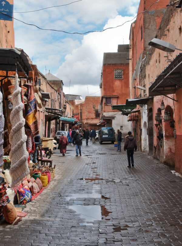 Explore the bustling streets of Marrakech with vibrant fabrics and traditional architecture in this lively market scene.